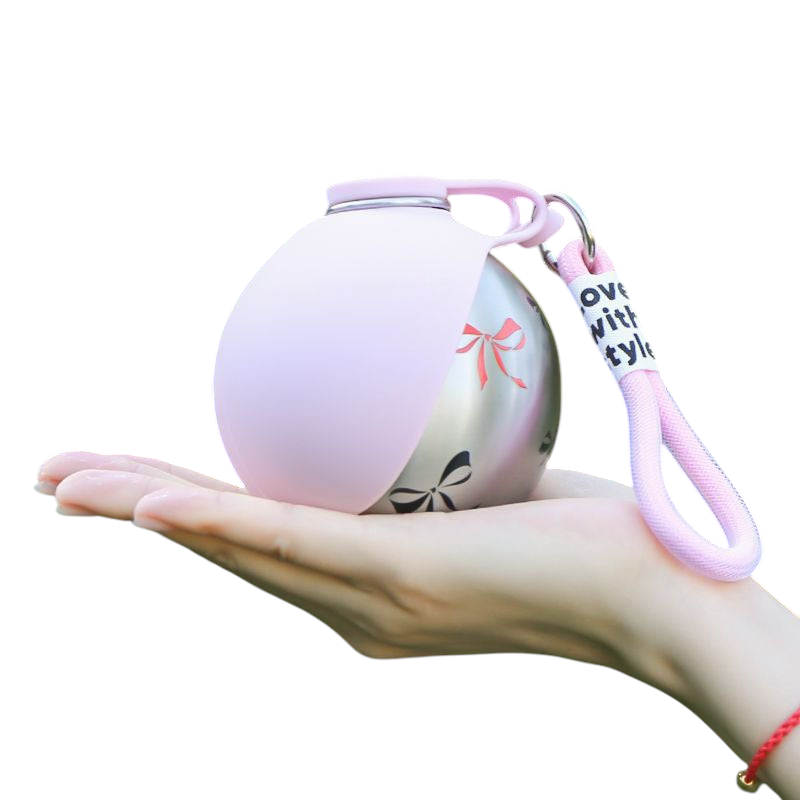 The Tailored Tail collapsible pink silicone and stainless steel pet water bottle held in a hand with a carry hook